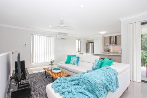 Beach Breeze Holiday House في ماكاي: غرفة معيشة مع أريكة بيضاء وتلفزيون