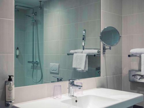 a bathroom with a sink and a shower and a mirror at Mercure Dinan Port Le Jerzual in Dinan