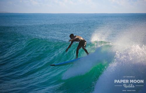 a man riding a wave on a surfboard in the ocean at Paper Moon Kudils in Arugam Bay