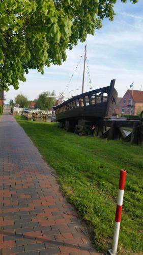 un barco sentado en el césped junto a una acera en Apartment am Obenende, en Papenburg