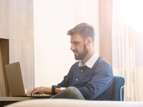 a man sitting at a table using a laptop computer at Novotel RJ Porto Atlantico in Rio de Janeiro