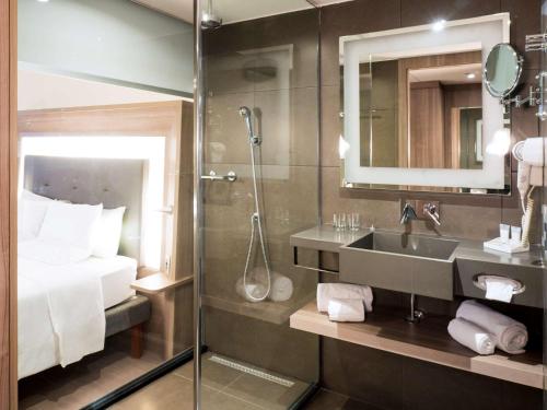 a bathroom with a shower and a sink and a bed at Novotel RJ Porto Atlantico in Rio de Janeiro
