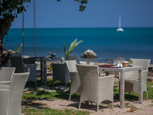 een tafel en stoelen op het strand met de oceaan bij Sea Dance Resort in Choeng Mon Beach