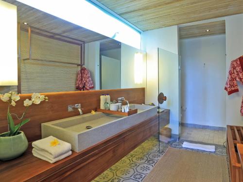 ein Badezimmer mit einem großen Waschbecken und einem großen Spiegel in der Unterkunft Jeeva Santai Villas in Senggigi 