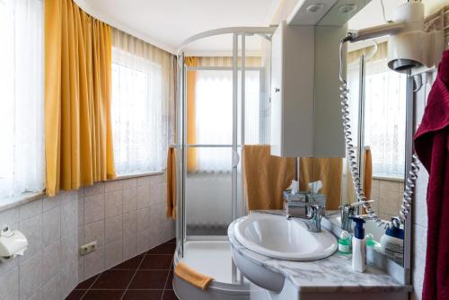 ein Bad mit einem Waschbecken und einer Dusche in der Unterkunft Hotel Adler in Wismar