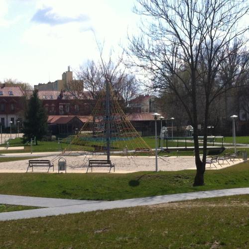 a park with a playground with benches and a tree at Pokoje AGA in Mikołajki