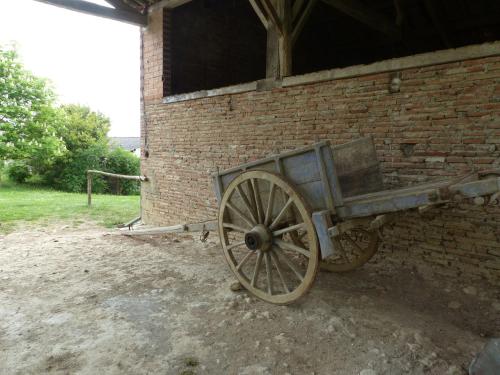 a wooden wagon leaning against a brick wall at Gites Souleilla de la Nine in Canens