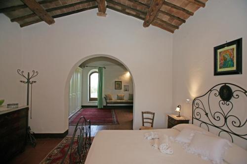 Un dormitorio con una cama blanca y un arco en Agriturismo Fonte Senesi, en Monticchiello