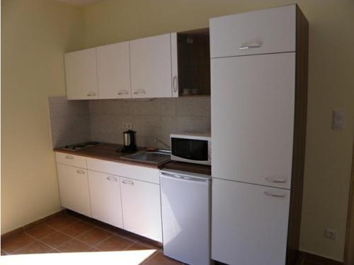 a kitchen with white cabinets and a white refrigerator at Anker Villa in Balatonszárszó