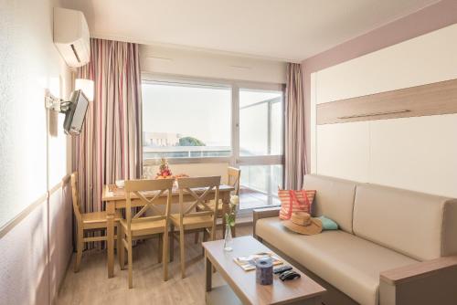 a room with a couch and a table with a dining room at Résidence Pierre & Vacances La Rostagne in Juan-les-Pins
