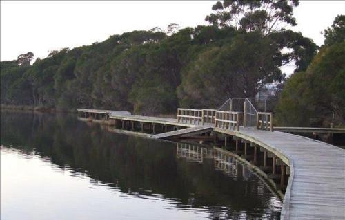 a wooden bridge over a body of water with benches at Snug Cove Villas in Eden