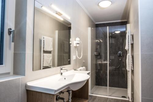 a white bathroom with a sink and a shower at Arpa Chalet in Santa Cristina in Val Gardena