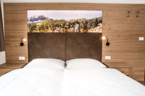 een slaapkamer met een wit bed met een foto erboven bij Arpa Chalet in Santa Cristina in Val Gardena