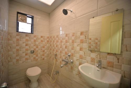 a bathroom with a sink and a toilet and a mirror at Hotel Radhe Krishna in Solapur