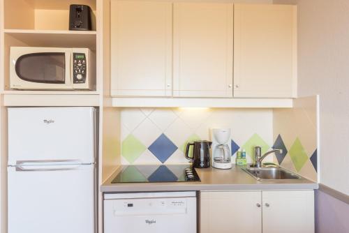 a kitchen with a white refrigerator and a microwave at Résidence Pierre & Vacances La Rostagne in Juan-les-Pins