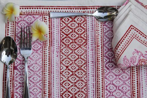 a table with forks and spoons on a pink and white table cloth at The Postcard Velha, Goa in Old Goa
