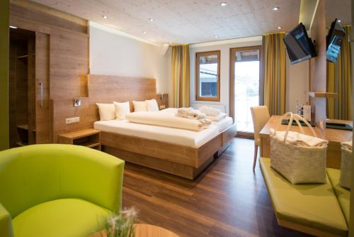 a bedroom with a bed and a green chair at Wellnesshotel Sonnenhof & Sonnhalde in Ühlingen-Birkendorf
