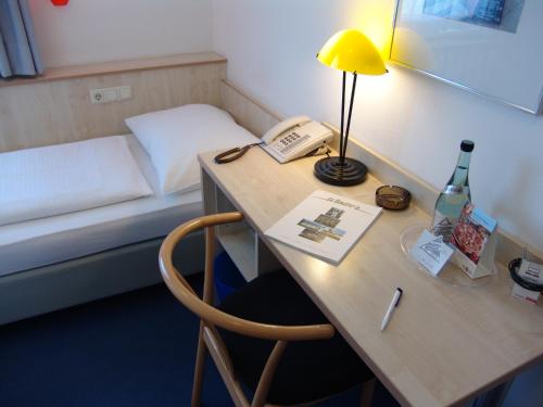 a room with a desk with a phone and a bed at enjoy hotel Berlin City Messe in Berlin