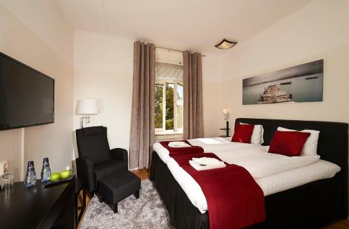 ein Hotelzimmer mit einem großen Bett und einem Stuhl in der Unterkunft Stadshotellet Kristinehamn in Kristinehamn
