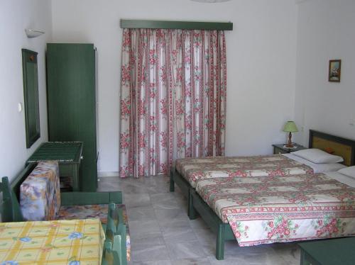 a bedroom with two beds and a window with curtains at Knossos in Panormos Rethymno