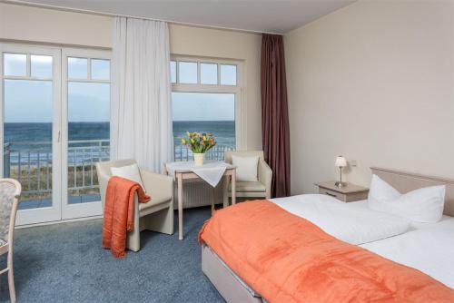 a hotel room with a bed and a view of the ocean at Strandhotel Dünenhaus in Juliusruh