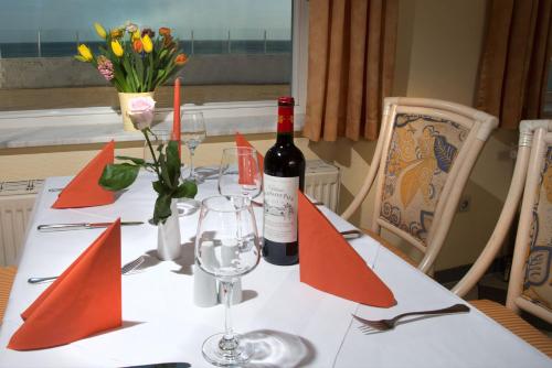a table with a bottle of wine and flowers on it at Strandhotel Dünenhaus in Juliusruh