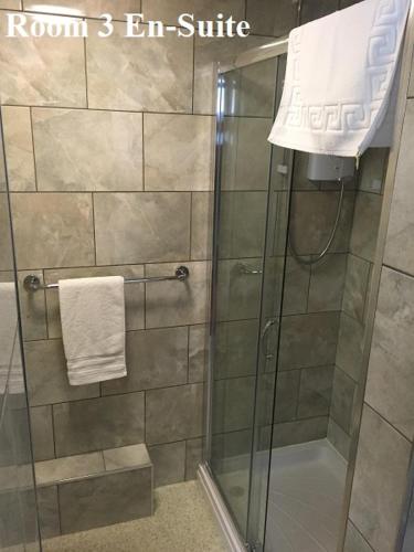 a bathroom with a shower with a glass door at The Arches Guest House in Whitby