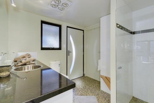 a white bathroom with a sink and a shower at Park Beach Retreat in Dodges Ferry