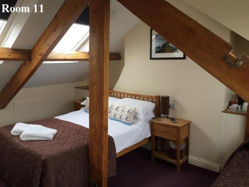 a attic room with a bed and a night stand at The Arches Guest House in Whitby