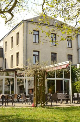 a building with tables and chairs in front of a building at Hotel Restaurant Le Paris in Mondorf-les-Bains