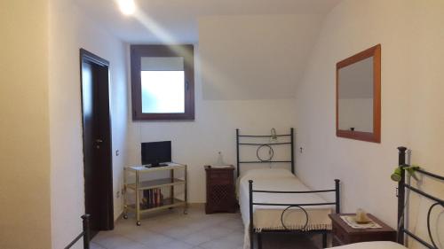 a bedroom with a bed and a desk with a television at Affittacamere Peonia in Oliena
