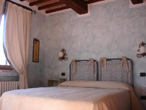 a bedroom with a bed with white sheets and a window at Agriturismo Borgo Montecucco in Todi