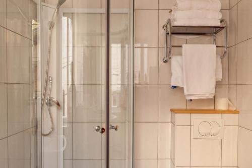 W łazience znajduje się prysznic i białe ręczniki. w obiekcie Hôtel Restaurant Les Alpins w mieście Saint-Julien-en-Beauchêne