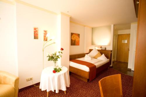 a hotel room with a bed and a table with flowers on it at ANGERHOF Kur- und Thermenhotel in Bad Wörishofen