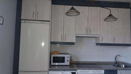 a kitchen with white cabinets and a microwave at PLAZA DE LA VILLA 24 in Rascafría