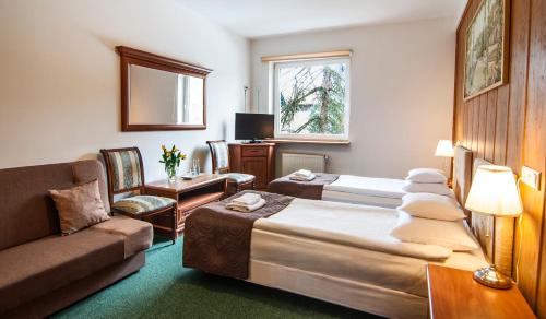 a hotel room with two beds and a couch at Hotel Artur in Kraków