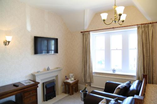 a living room with a couch and a fireplace at Keswick Park Hotel in Keswick