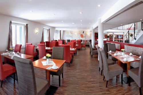 un restaurant avec des tables en bois et des chaises rouges dans l'établissement H+ Hotel Leipzig, à Leipzig