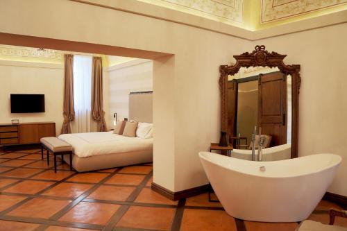 a bathroom with a tub and a bed and a mirror at Al Palazzetto in Tivoli