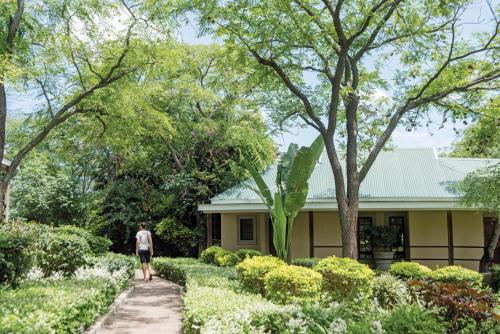a man walking down a path in front of a house at Perry's Bridge Hollow Boutique Hotel in Hazyview