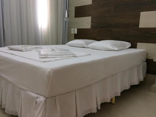a large white bed with white sheets and pillows at Hotel Beira Rio in Teófilo Otoni