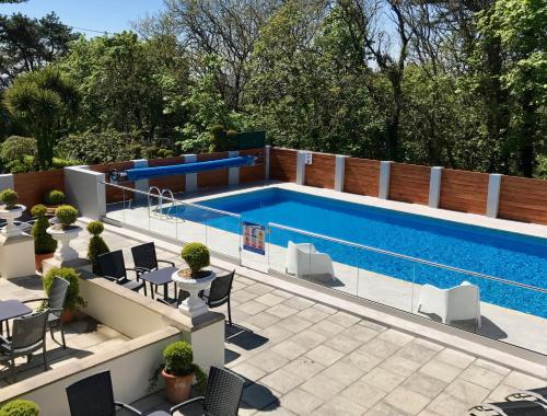 a swimming pool with tables and chairs next to at The Park Hotel in Tenby