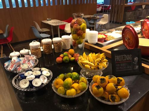 a counter with bowls of fruit on a table at Ibis Florianopolis in Florianópolis