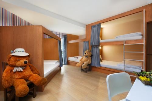 a large teddy bear sitting in a room with bunk beds at U Tiny Boutique Hotel Suvarnabhumi Bangkok - SHA Plus in Lat Krabang