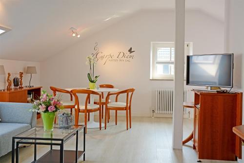 sala de estar con mesa, sillas y TV en Hotel garni Kaiserstuhl, en Ihringen