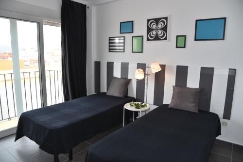 two beds in a room with a window at Triplex T3 SOUTH APARTMENT in Tarifa