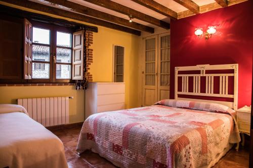 1 dormitorio con 2 camas y pared roja en Viviendas Rurales Las Fontanias, en Cóbreces