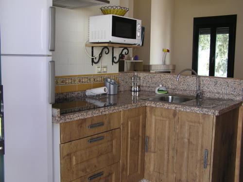 Una cocina con fregadero y refrigerador blanco. en Alojamiento Rural El Chaparral, en Setenil
