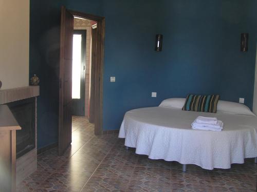 1 dormitorio con 1 cama con paredes azules y chimenea en Alojamiento Rural El Chaparral, en Setenil