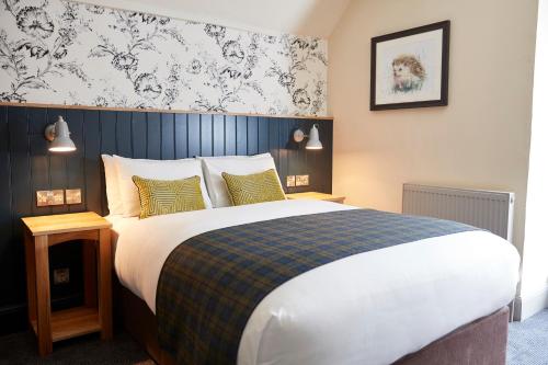 1 dormitorio con 1 cama grande y pared azul en Swan Hotel by Greene King Inns en Thaxted